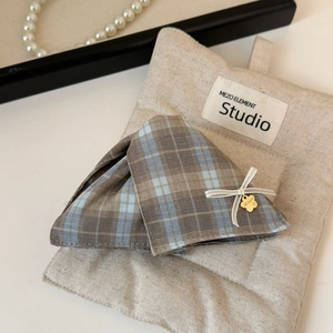 Close-up of British plaid fabric hair claw clip with golden flower tag and white bow detail