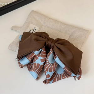 Detail of elegant oversized bow hair clip featuring mixed patterns and beaded tassels