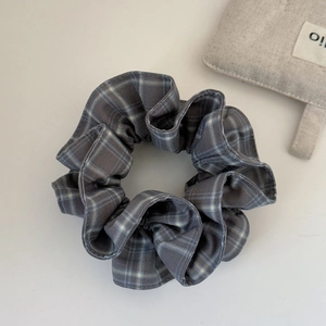 Detailed macro view of dark grey plaid scrunchie with soft cotton blend textile texture