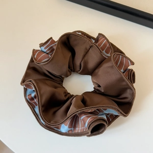 Detail of silk texture and blue geometric patterns on a brown oversized scrunchie