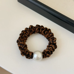 Chouchou élastique léopard avec grande perle blanche sur un fond blanc propre