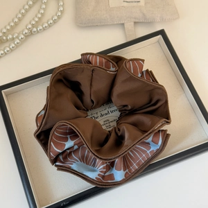 Elegant large brown satin scrunchie with blue leaf pattern on a decorative display tray
