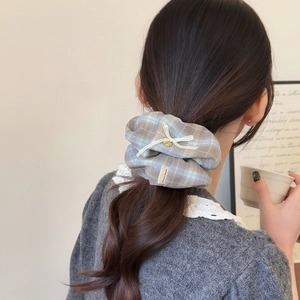Blue and grey plaid scrunchie with bow and gold heart pendant on model's ponytail