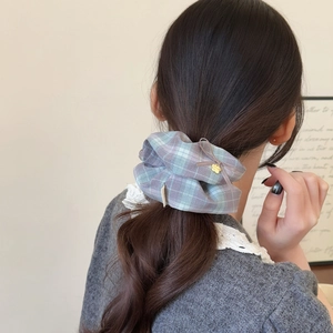 Plaid scrunchie with purple ribbon bow and gold bear pendant worn on a ponytail