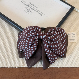 Detail of retro checkered hair bow with delicate small beads on woven texture background