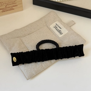 Détail d'un bandeau en velours noir avec boucle dorée et élastique à cheveux assorti