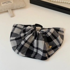 Detail of French plaid bow hair claw with a small gold metal logo tag on fabric