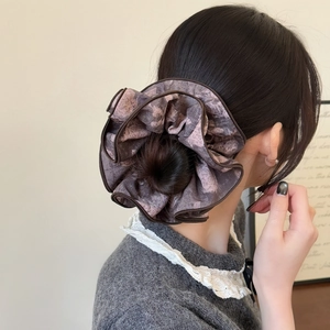 Détail d'un chouchou géant vintage à imprimé rose porté sur un chignon classique
