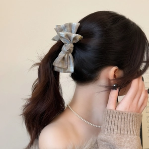Elegant brown plaid fabric bow hair clip shown on a low ponytail for women