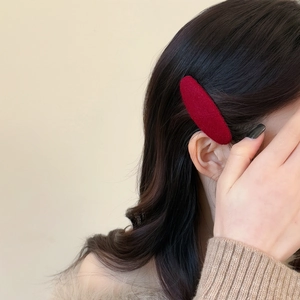 Elegant burgundy velvet oval hair clip shown on model with long wavy brown hair