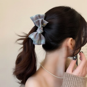 Elegant plaid bow hair clip for women with a subtle golden charm on a ponytail