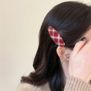 Red and white checkered plaid hair clip worn on model with elegant tweed texture