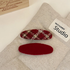 Red plaid and solid crimson velvet hair clips set on a warm beige linen background