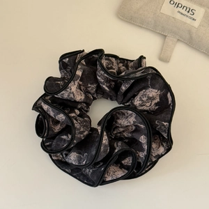 Détail d'un chouchou vintage à imprimé floral rose avec bords noirs à volants
