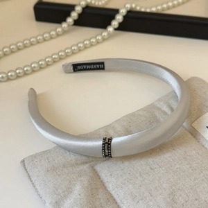 Close-up of silver-gray satin headband featuring three rows of sparkling diamond-set metal rings