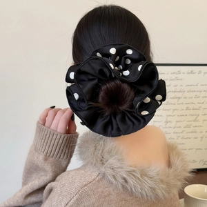 Detail view of a black satin scrunchie with white polka dots worn on a stylish bun