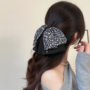 Floral print bow hair clip with double-layer design and hanging beads on black wavy hair