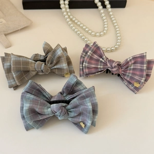 Detail view of fabric bow hair clips with plaid patterns and gold flower charms