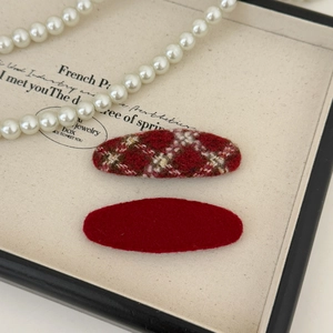 Macro shot of red plaid and felt fabric oval hair clips on a jewelry display tray