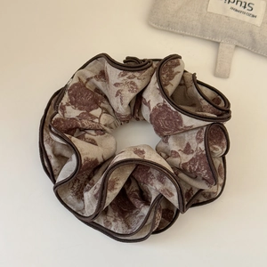 Détail d'un chouchou vintage à imprimé rose avec volants superposés et bordure brune