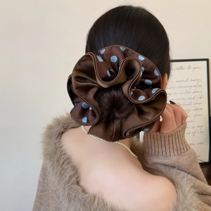 Detail of a brown polka dot oversized hair scrunchie with a glossy satin-like texture