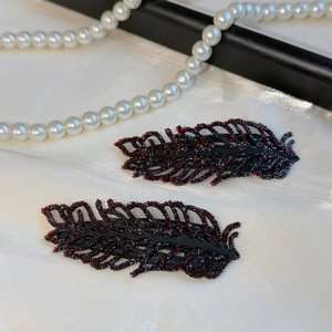 Macro shot of rhinestone leaf hair clips featuring sparkling crystals on black mesh base