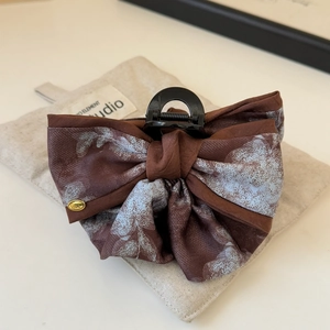 Détail de la pince à cheveux noeud en soie avec pendentif doré gravé love sur tissu