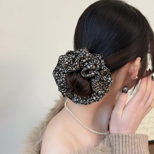 Close-up of floral print scrunchie showing fabric texture and double-layer design on a hair bun