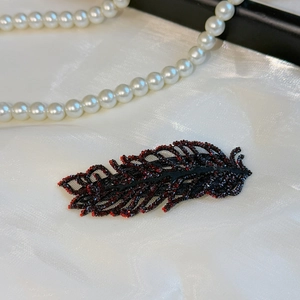 Detailed close-up of crystal leaf hair clip with dark red rhinestones on silk