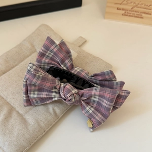 Detail of pink plaid fabric bow clip with gold bear pendant and large banana clip
