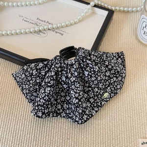 Close-up of a floral bow hair claw clip on a woven mat with French vintage style