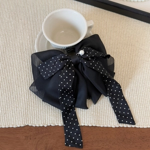 Détail de la pince à cheveux à pois noirs avec nœud élégant et décoration de perle