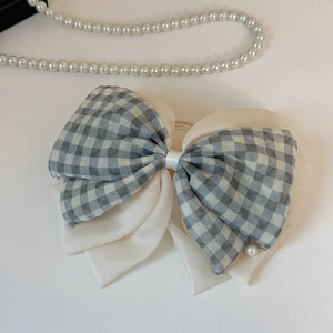 Détail de pince à cheveux à double nœud à carreaux gris clair avec pendentif perle