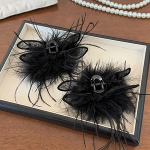 Detail of elegant black feather hair clips with mesh flowers on a jewelry tray