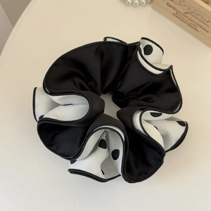 Detail of black and white polka dot scrunchie with satin texture and overlocked edges