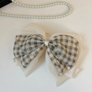 Détail d'une barrette à nœud double couche avec motif à carreaux et gouttes de perles blanches