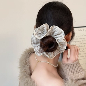 Chouchou oversize à carreaux beige élégant porté dans une coiffure en chignon chic