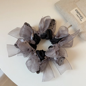 Détail d'un chouchou en organza gris avec nœuds à pois noirs et ruban élégant