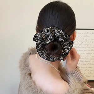 Détail d'un chouchou en mousseline fleurie porté en chignon pour un style élégant