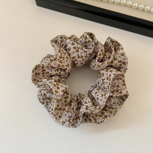 Detailed macro view of retro floral hair scrunchie with soft pleats and cotton texture