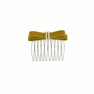 Détail du peigne à cheveux à nœud en velours vert moutarde avec perles blanches et dents