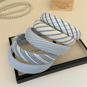 Detail view of five assorted light blue fabric headbands with striped and plaid patterns