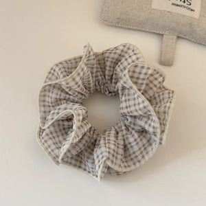 Gros plan détaillé d'un chouchou en tissu à carreaux marron et blanc avec plis doux