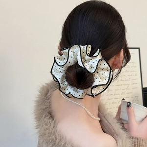Chic black and white polka dot oversized scrunchie hair accessory worn on a stylish bun