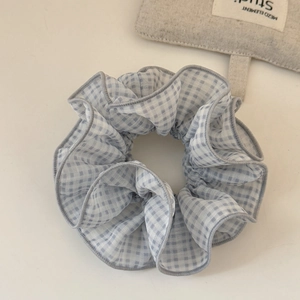 Détail de la texture du tissu vichy bleu clair et des coutures délicates du chouchou