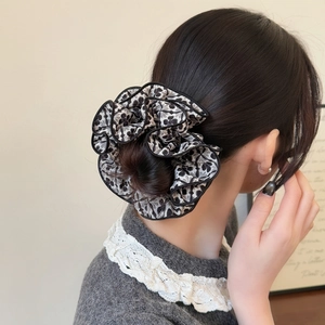 Elegant vintage black and white floral scrunchie worn on a messy bun hairstyle