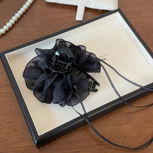 Details von elegantem schwarzen Blumen-Haarclip aus Netzstoff auf weißem Tablett