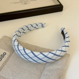 Detailed view of blue and white plaid fabric headband on a rustic linen background