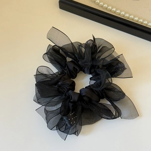 Détail d'un chouchou en organza noir orné de strass brillants et de couches de mesh translucide
