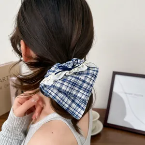 Detailed close-up of blue plaid scrunchie with lace trim and bow worn on a low ponytail